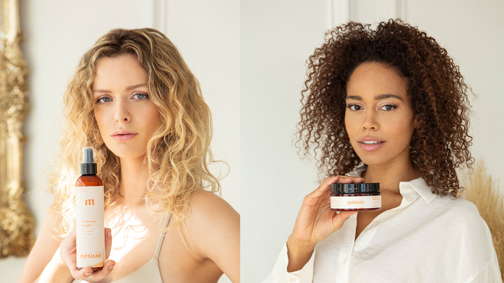 mixed girl and white girl with curly hair holding metisse natura products, the rice water detangler and the curl defining cream with shea butter castor oil and avocado oil, vegan, clean, and organic hair care products.